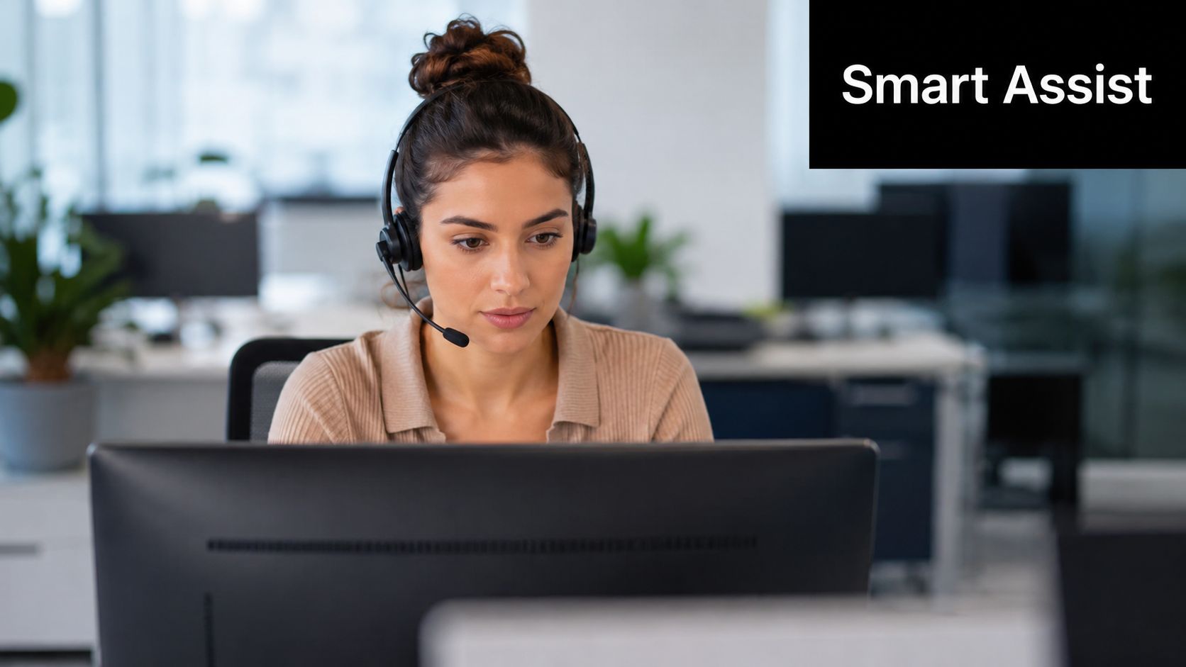 A professional customer service agent wearing a headset while working at a computer in an office.